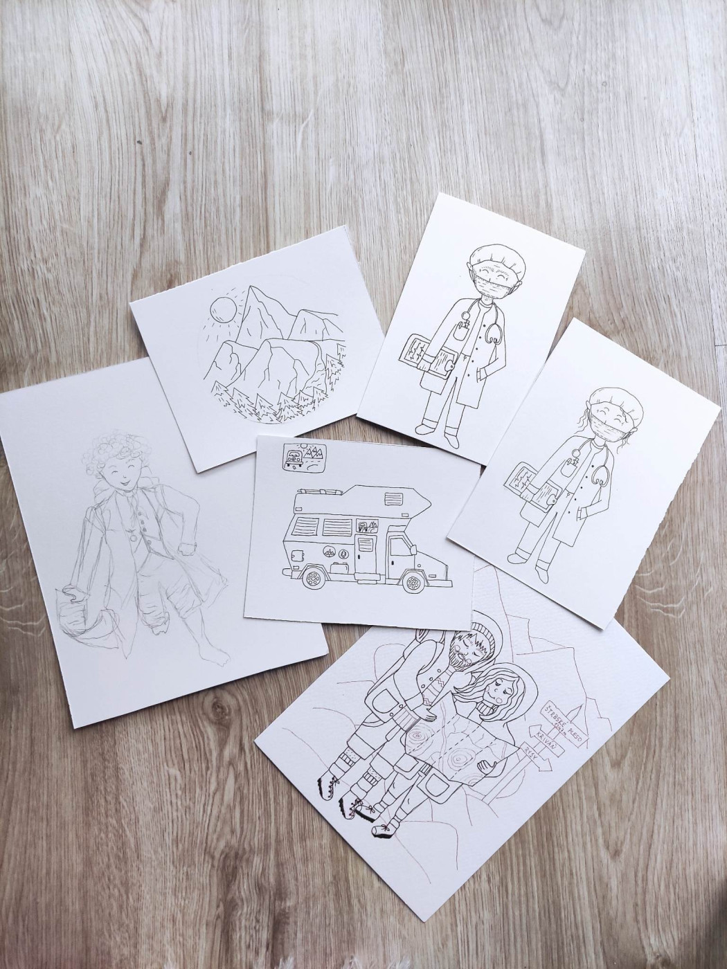 Zblízka nafotená kôpka jedinečných ilustrácií, ktoré boli ručne nakreslené fixkou a čakajú na svoje akvarelové vyfarbenie. Tieto predlohy sú základom pre naše originálne motívy na hrnčekoch Lesovik, čo podčiarkuje ich ručný a autorský pôvod.